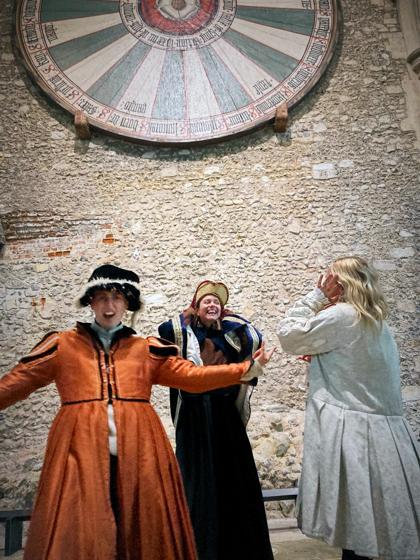 Crew in Tudor costume laughing beneath the medieval Round Table at Winchester Great Hall at the end of the Waitrose shoot.